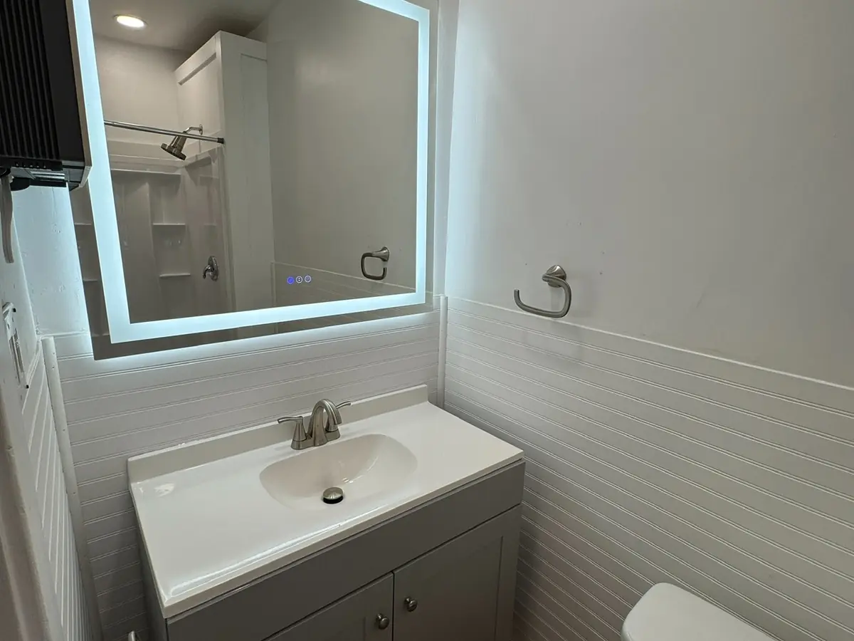 A bathroom with a backlit mirror above the vanity.