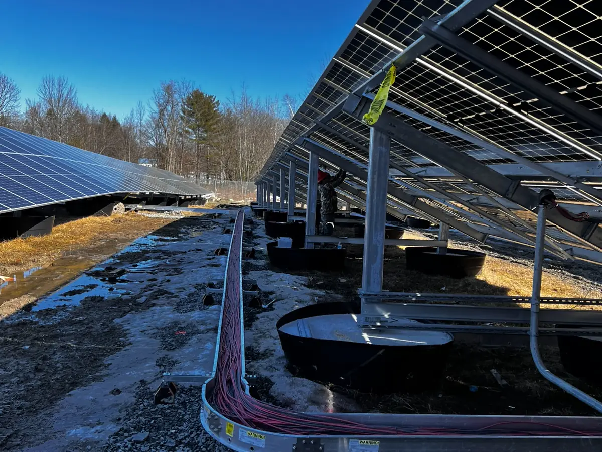A ground-mounted solar array with conduit runs feeding the combiner boxes.