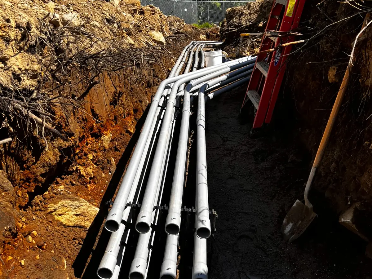 A bundle of underground conduits laid in an open trench before backfilling.